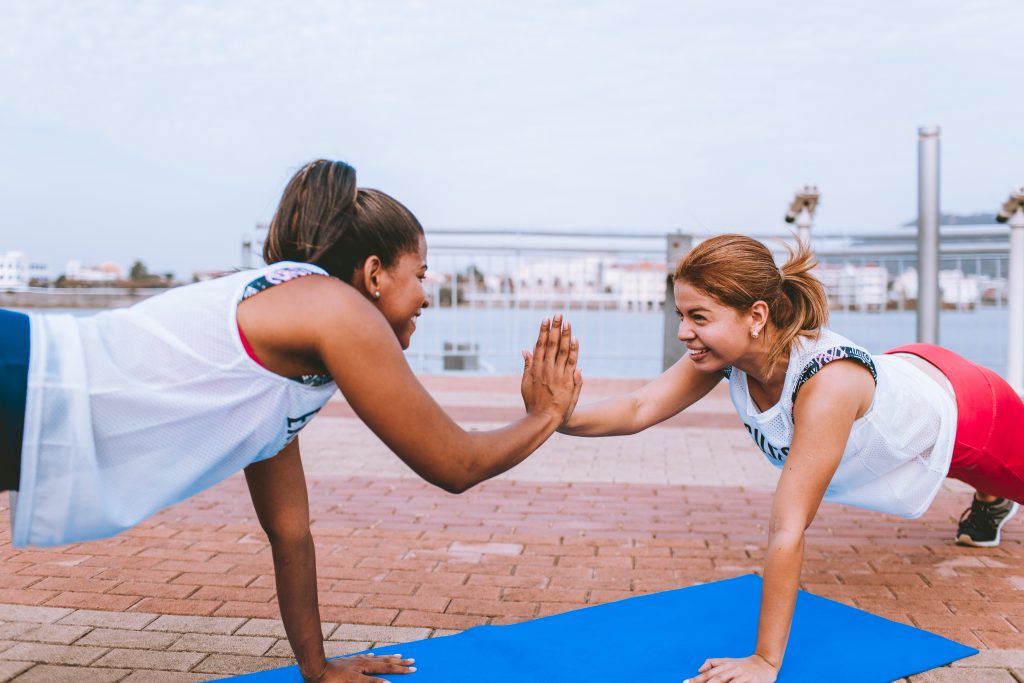 Two woman giving each other a high five while exercising